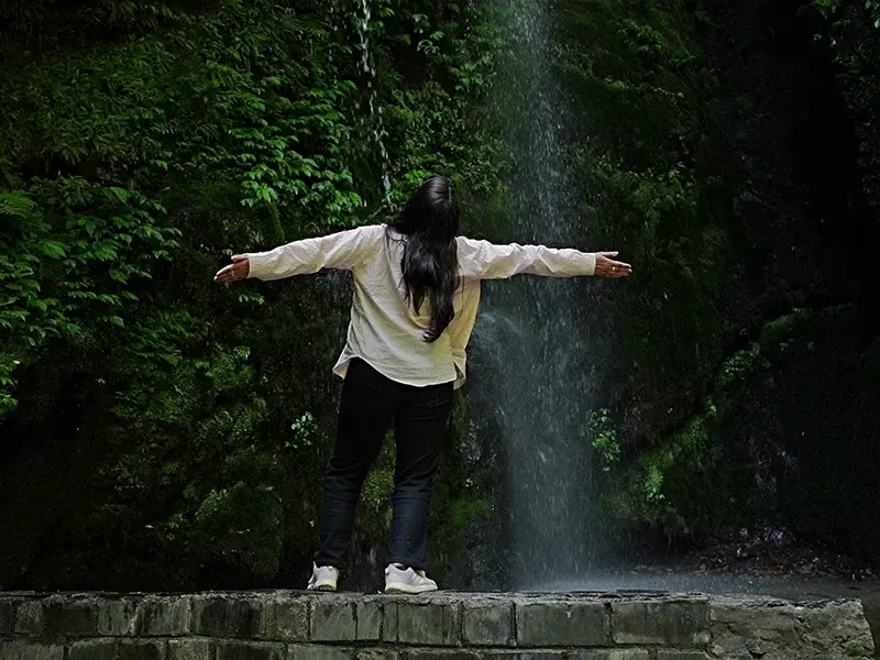 Traveler walking on forest path towards Jibhi Waterfall
